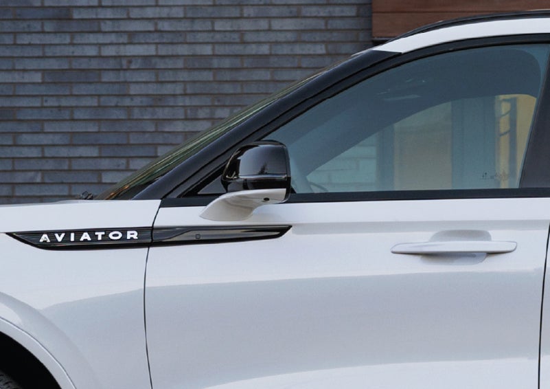 The driver’s side door and fender badging of a white 2026 Lincoln Aviator® SUV are showcased. | Hines Park Lincoln in Plymouth MI