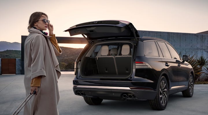 A woman approaches a 2026 Lincoln Aviator® SUV with its rear liftgate open. | Hines Park Lincoln in Plymouth MI