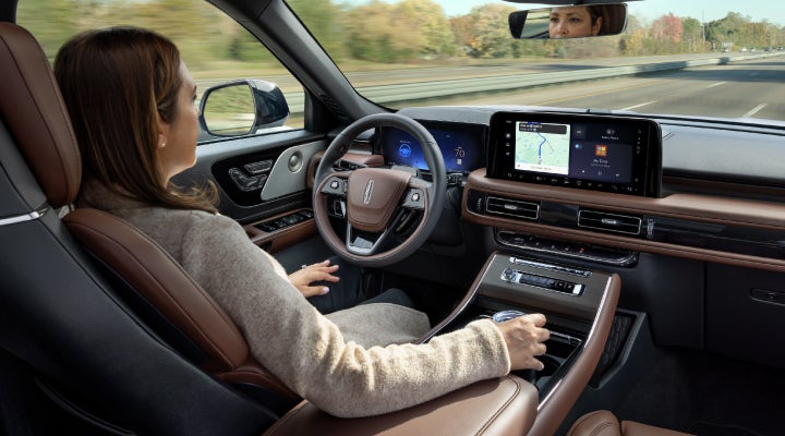 A 2026 Lincoln Aviator® SUV is being driven hands-free on a highway near a forest | Hines Park Lincoln in Plymouth MI