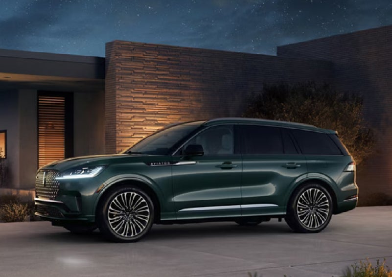 A green 2027 Lincoln Aviator® SUV is parked outside a contemporary home. | Hines Park Lincoln in Plymouth MI