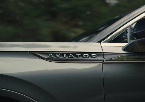 The driver’s side door and fender badging of a gray 2027 Lincoln Aviator® SUV are showcased. | Hines Park Lincoln in Plymouth MI