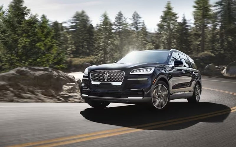 Lincoln Aviator driving up a mountain road with the sun shining brightly from Lincoln Dealer near Brighton MI