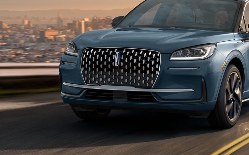Closeup of front of Lincoln Corsair driving with the cityscape in the background from Lincoln Dealer near Plymouth, MI