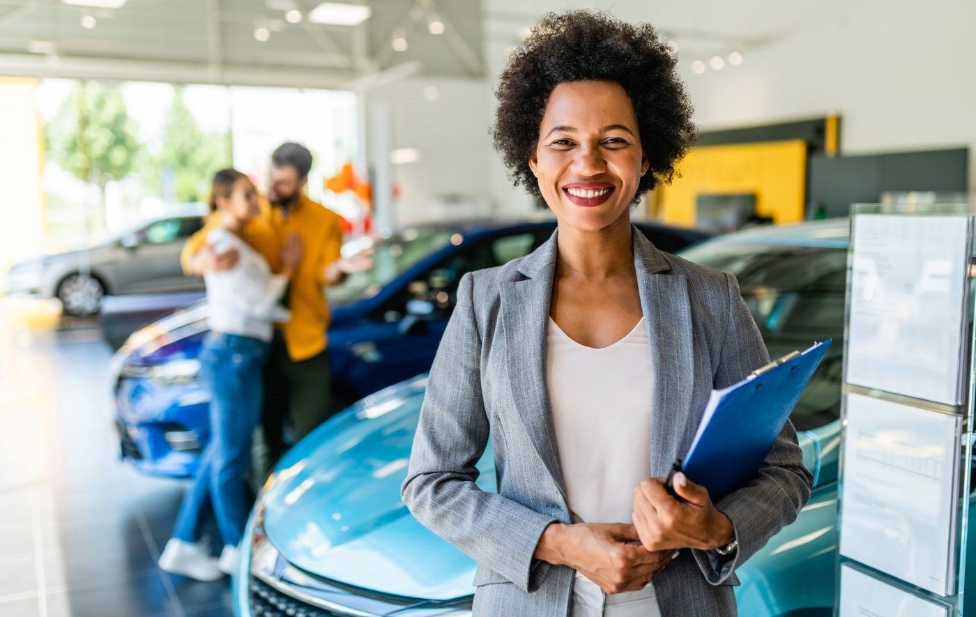 Finance Team member smiling after helping couple in the background with Lincoln financing options