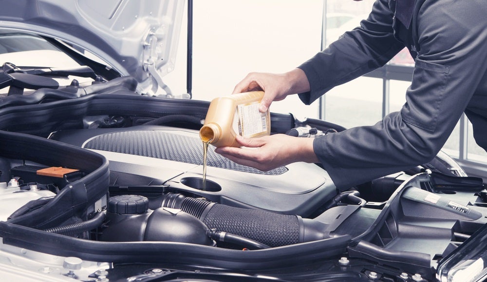 Lincoln Certified Technician pouring fresh oil into vehicle during oil change at Service Center