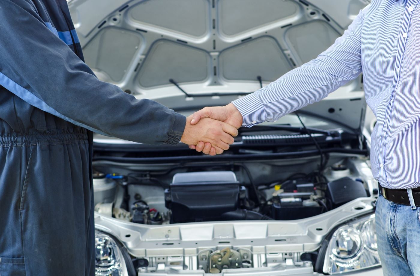 Professional Lincoln Technician shaking hands with customer in Service Center after discussing maintenance repairs